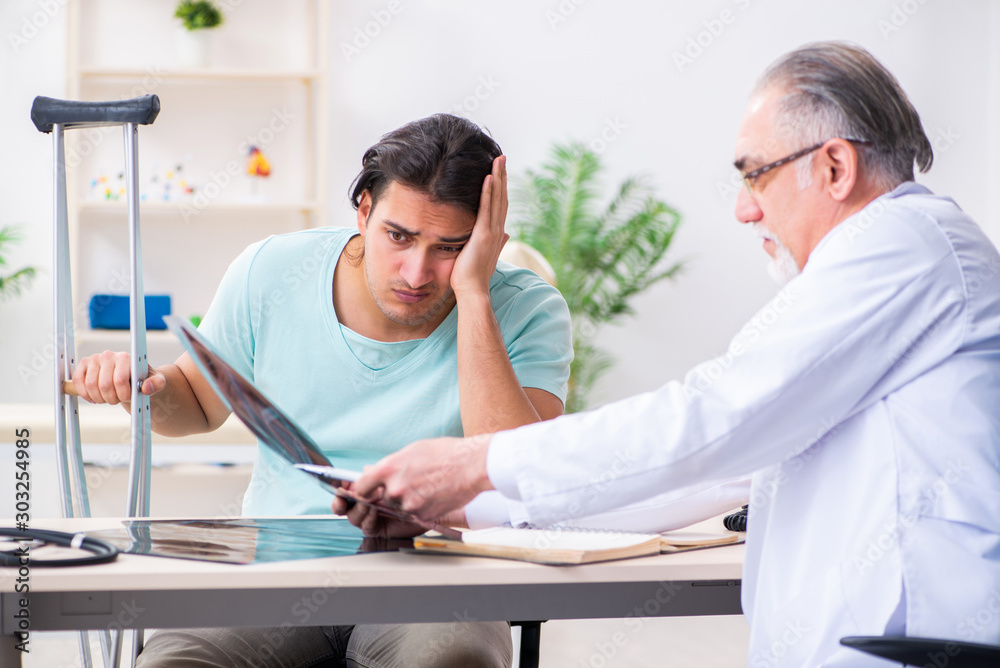 Fototapeta premium Young leg injured male patient visiting old doctor
