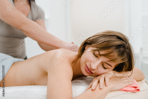 Qualified female therapist doing massage and treating pain in back