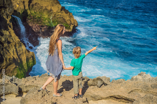 mother and son tourists against the background of the sea Angel's Billabong in Nusa Penida, Bali, Indonesia. Travel to Bali with kids concept photo