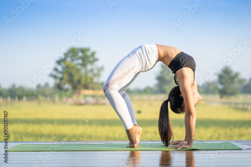 Young Asian playing and pose Yoga on the floor with nature rice field and blue sky background, Yoga Concept.