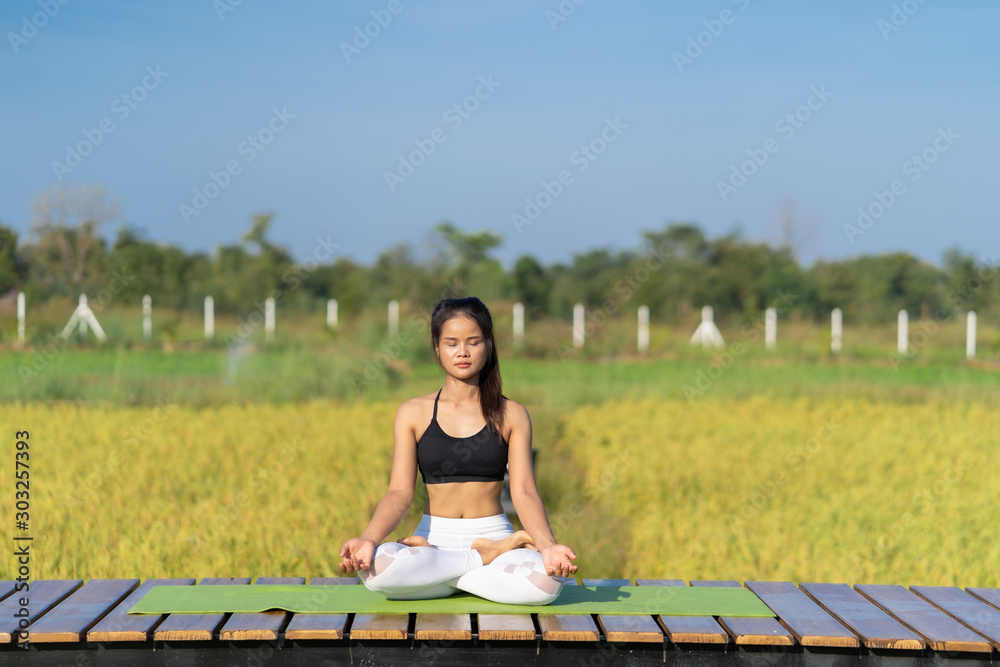 Young Asian playing and pose Yoga on the floor with nature rice field and blue sky background, Yoga Concept.