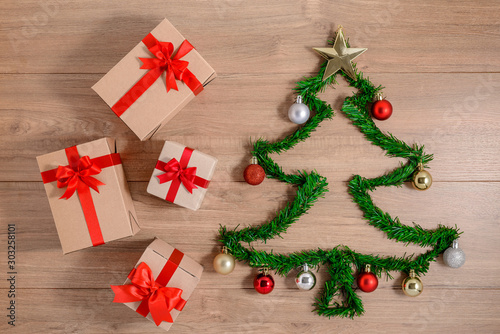 Creative winter layout made with evergreen tree branches and ornament, gift boxes on wooden background