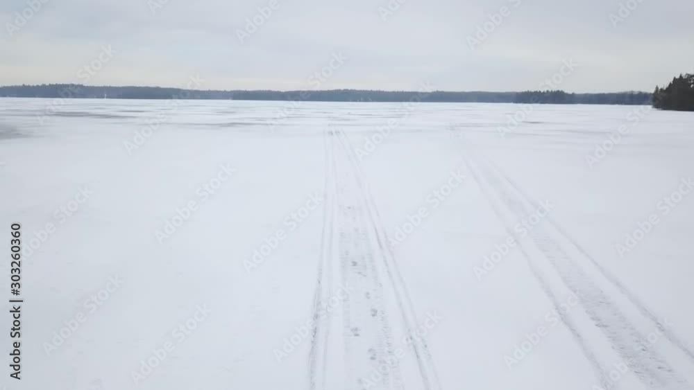 Aerial drone view flying above frozen ice lake in winter Aerial drone view flying above frozen ice lake in winter
