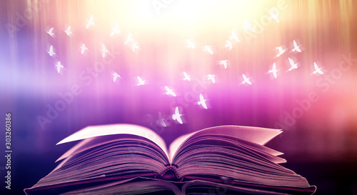 Imagine opening an old book blurred with magic power on the table and the English alphabet floating above the book with magic light as a beautiful background design. © Ping198