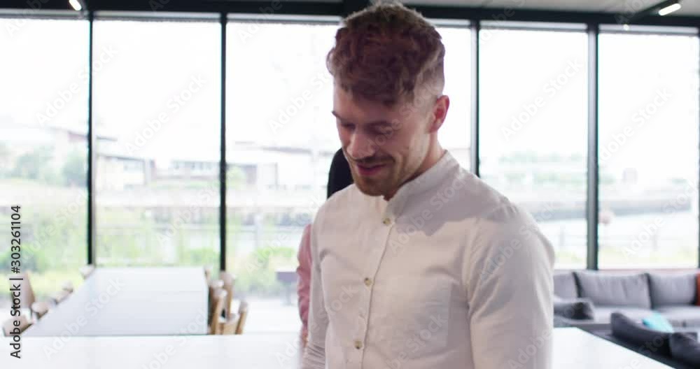 4K Young businessman walking through trendy office, looking at tablet & smiling. Slow motion. 4K Young businessman walking through trendy office, looking at tablet & smiling. Slow motion.