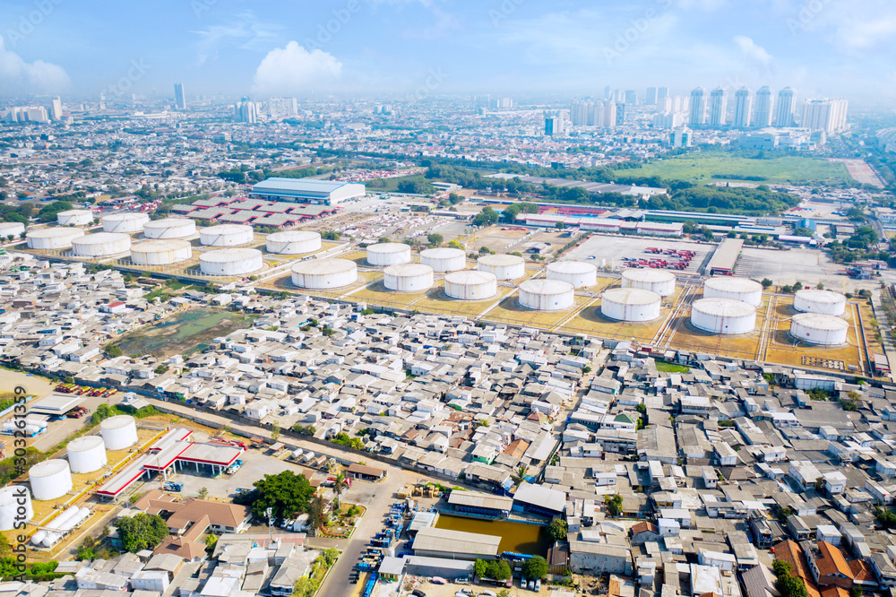 Fototapeta Aerial view of oil storage tanks near crowded houses