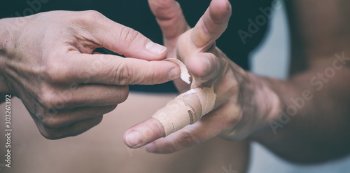 Rock climber wraps fingers with tape.