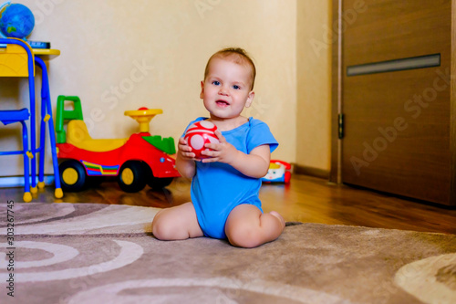 Fotografia Beautiful baby boy sitting and playing with red boll at home.