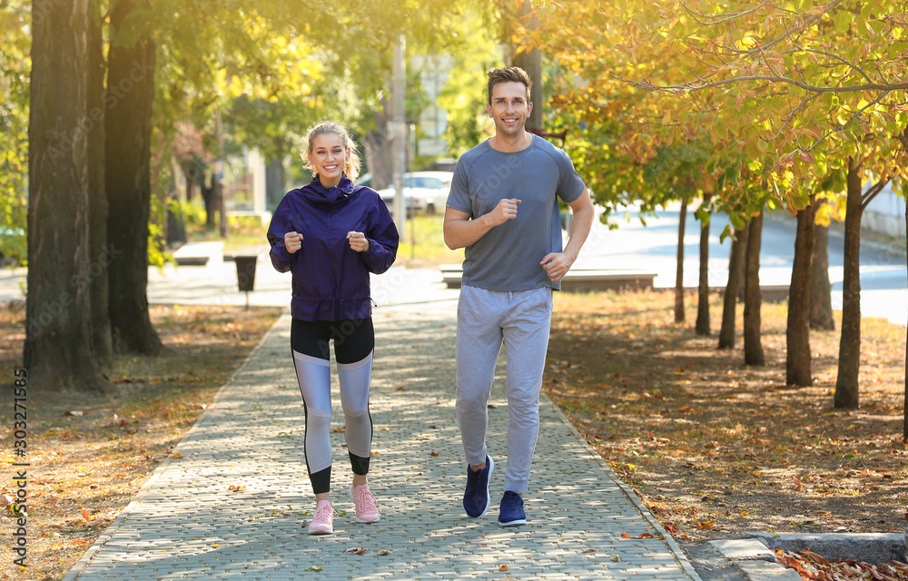 Fototapeta premium Sporty young couple running in park