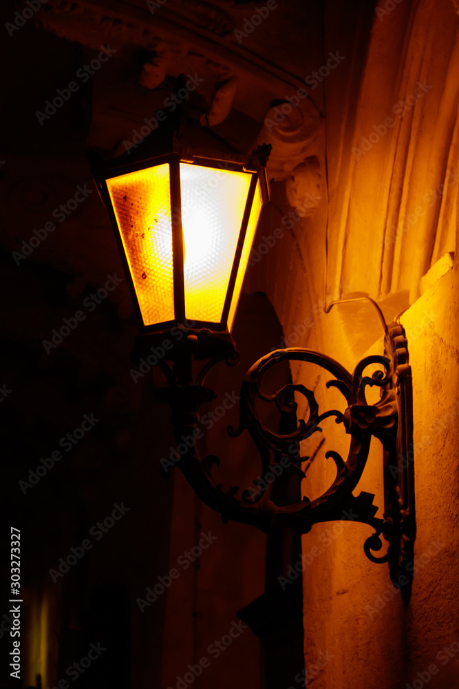 Lighted vintage street lantern on the wall of a house at night
