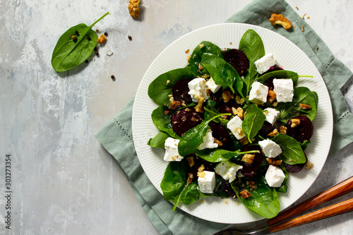 Vitamin snack. Salad with spinach, feta cheese, beetroot and walnut, vegetable oil sauceon a concrete table. Top view flat lay background. Copy space. photo