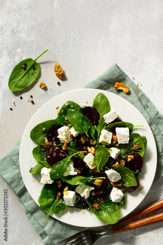 Vitamin snack. Salad with spinach, feta cheese, beetroot and walnut, vegetable oil sauceon a concrete table. photo