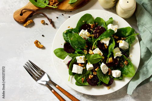 Vitamin snack. Salad with spinach, feta cheese, beetroot and walnut, vegetable oil sauceon a concrete table. Copy space. photo