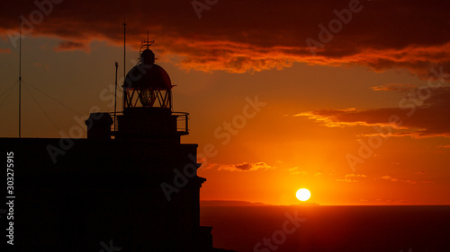 Billede på lærred Cape Prior Silhouetted Lighthouse against Orange Sky Sunset and Sun at the Horiz