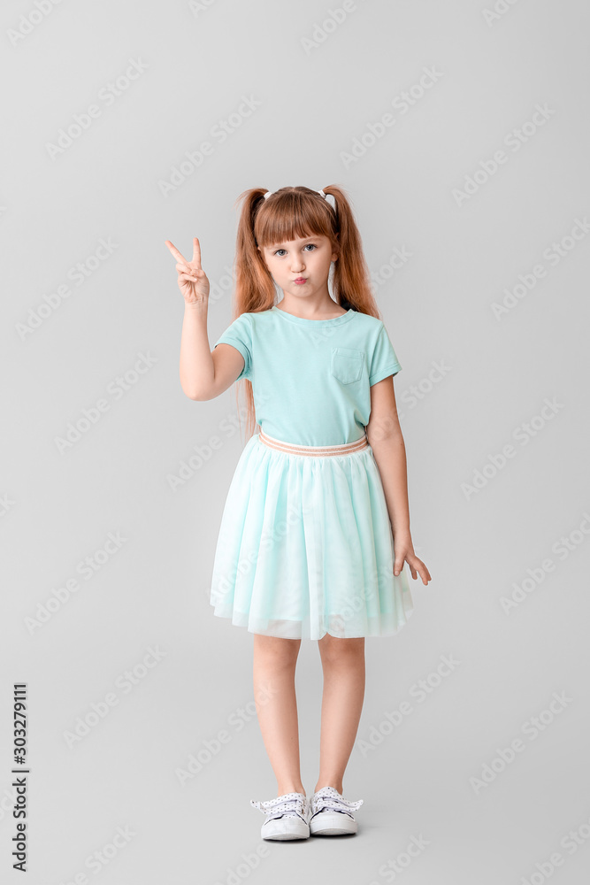 Cute little girl showing victory gesture on light background Cute little girl showing victory gesture on light background