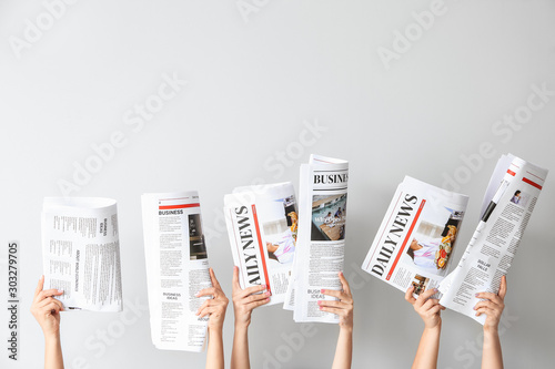 Female hands with newspapers on light background photo