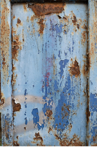 A section of a rusty, corroded, and worn steel sliding gate in front of a residential community.