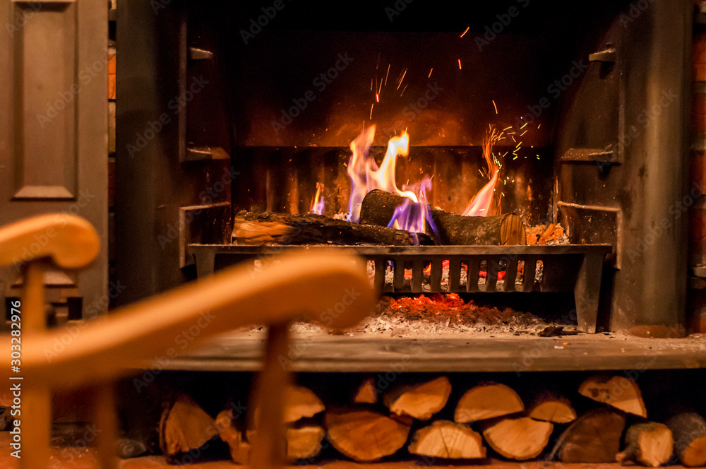 Home comfort. Rocking chair near the fireplace. Photo of interior of room. Rocking chair in the living room with decorated modern fireplace Home comfort. Rocking chair near the fireplace. Photo of interior of room. Rocking chair in the living room with decorated modern fireplace
