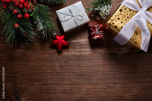 Christmas tree branches and gifts on wooden background.
