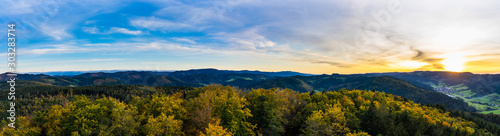 Germany, XXL panorama of endless aerial view above tree tops in black forest nature landscape in colorful autumn mood in warm sunset light, a paradise.