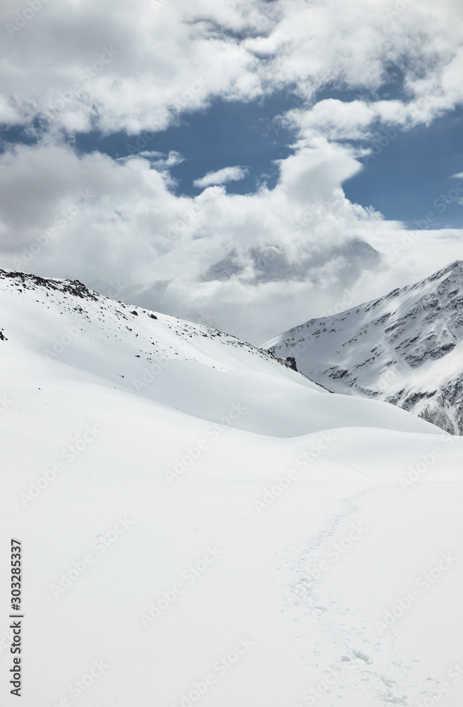 Obraz premium Snowy mountains and clouds in the sky on a sunny day