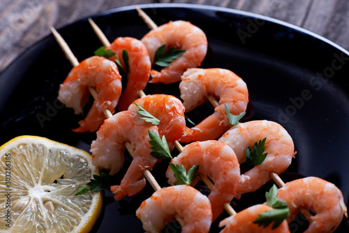 Boiled shrimp in a black plate on gray boards.