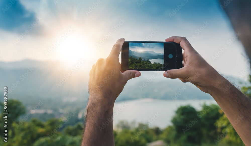 Smartphone hands shooting a beautiful landscape with sunset, travel concept and photography