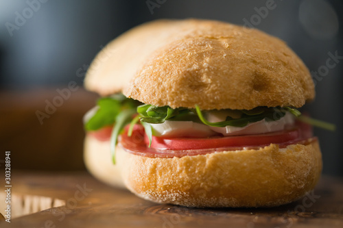 ciabatta sandwich with salami and mozzarella cheese on olive board