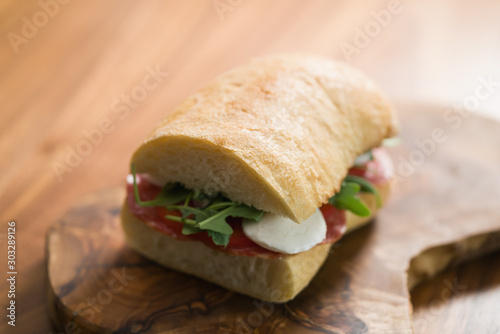 ciabatta sandwich with salami and mozzarella cheese on walnut table