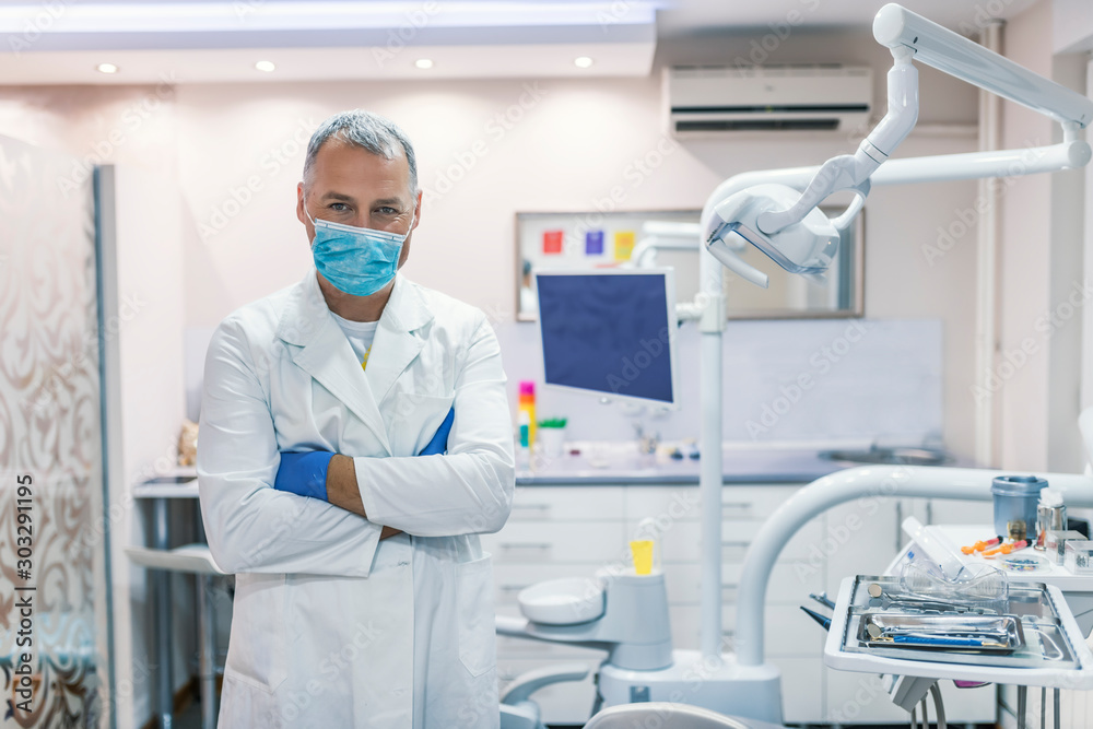 Male dentist standing with his hands crossed and looking at camera Male dentist standing with his hands crossed and looking at camera