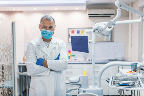 Male dentist standing with his hands crossed and looking at camera