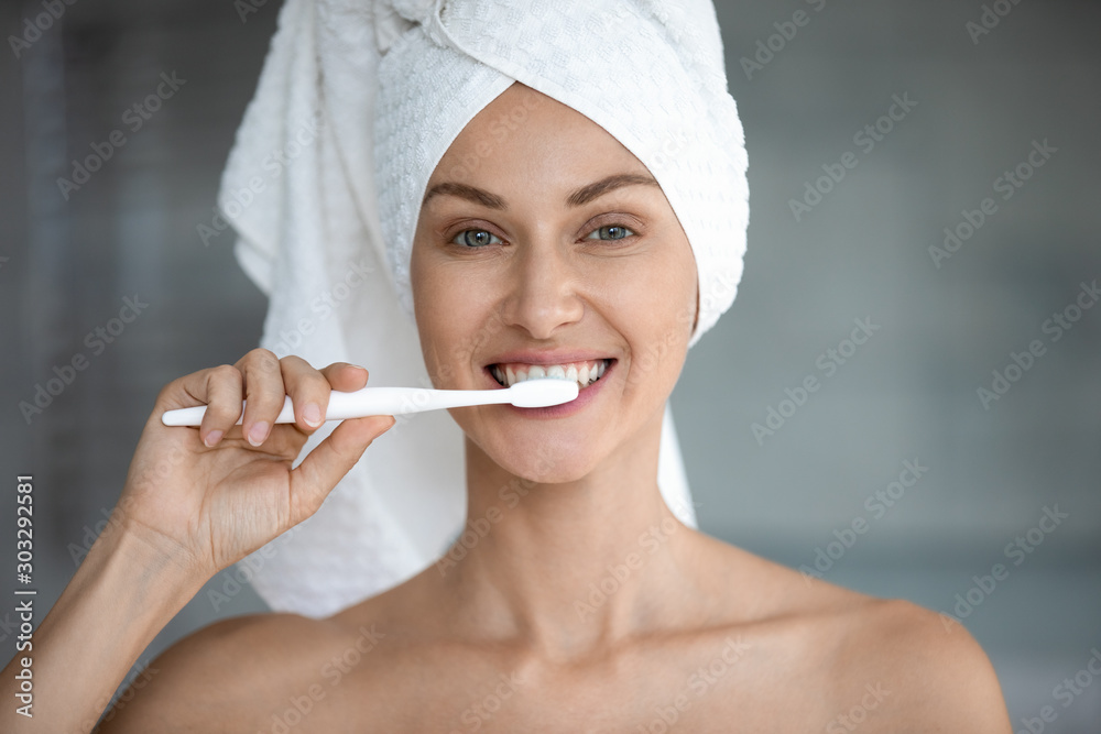 Happy young woman brushing healthy teeth looking at camera Happy young woman brushing healthy teeth looking at camera