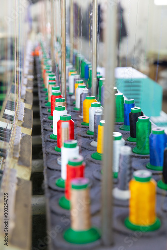 Close up with multicolored spools on an industrial sewing machine