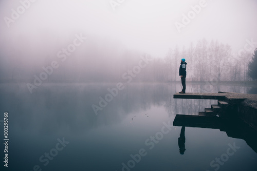Man standing on a deck above a misty lake. Depression and suicide concept.