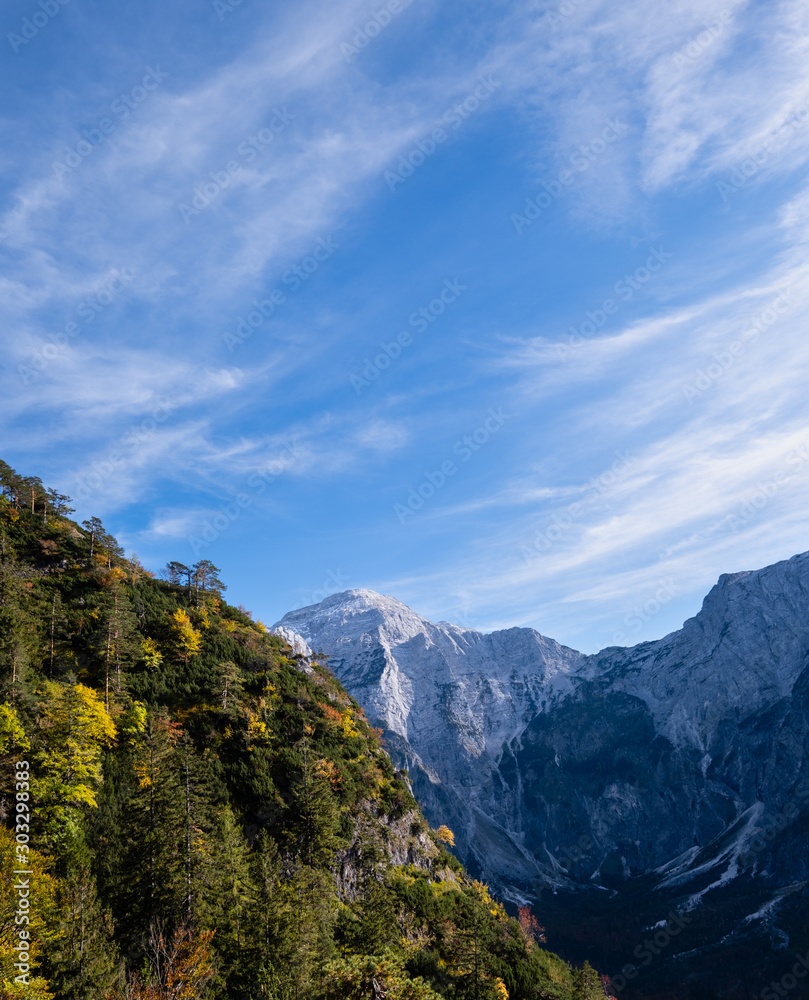 Sunny idyllic sky above colorful autumn alpine scene. Peaceful rocky mountain view from hiking path near Almsee lake, Upper Austria.