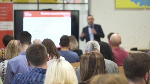 Wallpaper Mural business coach man lecturer giving speech training to people in audience. male speaker giving presentation and lecture. conference hall. Rear view of participants Torontodigital.ca