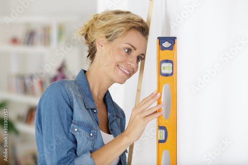 Фотография woman checking level of wall flatness