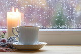 Porcelain cup of tea and a candle by the window.