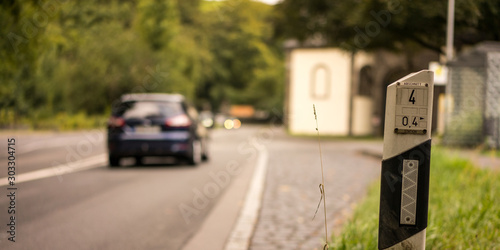 Leitpfosten an einer Landstraße mit Auto im Hintergrund