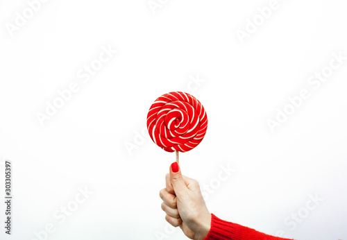 Red and white spiral lollipop in women hand isolated on white background