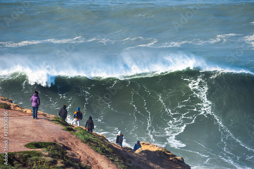 People watching big waves in Nazare, Portugal. In this place the biggest waves in the world due to the underwater canyon