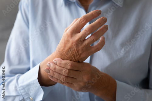 Senior lady massaging hand suffering from rheumatoid arthritis concept, closeup photo