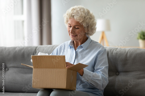 Foto Smiling elderly woman customer receive post shipment parcel at home