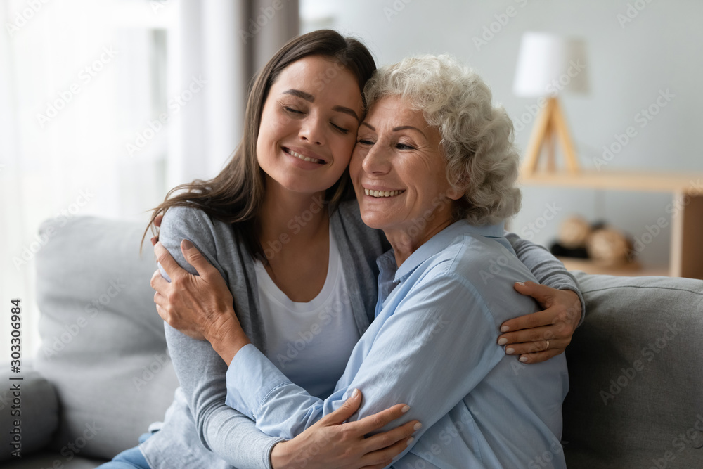Affectionate young granddaughter and elderly grandma cuddling bonding at home Affectionate young granddaughter and elderly grandma cuddling bonding at home