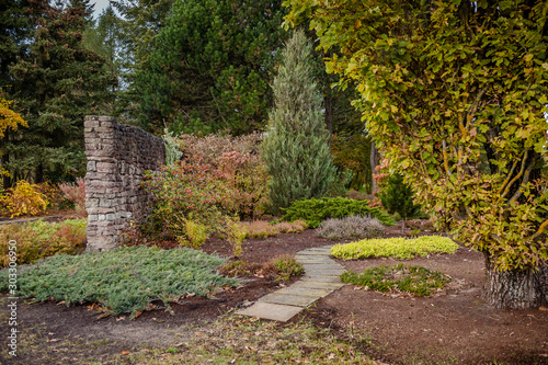 Beautiful autumn garden design, with conifer trees and stone path. Autumn landscape. Fall. National Botanic Garden of Latvia in Salaspils..