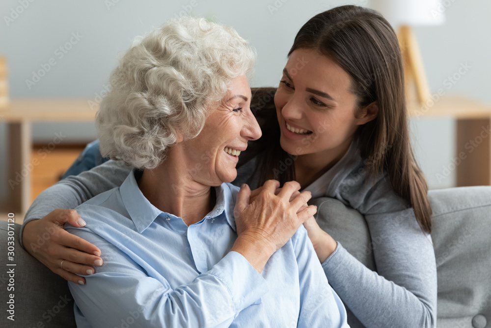 Loving young woman granddaughter hugging senior grandma giving care Loving young woman granddaughter hugging senior grandma giving care