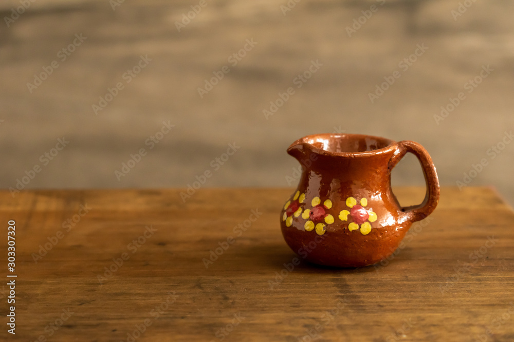 Mini traditional mexican clay cups on a wooden surface against a rocky background Mini traditional mexican clay cups on a wooden surface against a rocky background