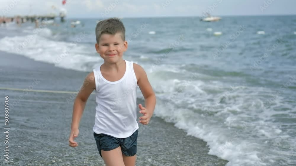 Happy cute child boy running on beach washing sea waves feeling positive emotion slow motion Happy cute child boy running on beach washing sea waves feeling positive emotion slow motion