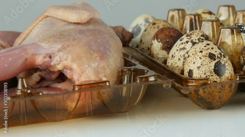Fresh meat of quail in a plastic brown tray next to the quail eggs on a white background photo
