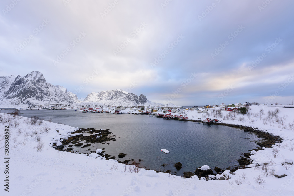 Beautiful village of Reine in Lofoten Islands, Norway. Snow covered winter landscape at sunset. Amazing tourist attraction in the polar circle. Panoramic view.